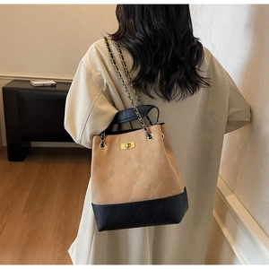 Detail view of quilted color-block bucket bag with chain strap worn by a model
