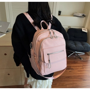 Pink lychee grain leather backpack with metallic chain and woven patterned shoulder strap