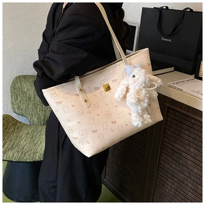 Detail of cream tote bag with bear print and cute plush bunny pendant accessory