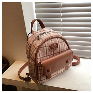 Close-up of pink plaid mini backpack with leather accents on a white window sill