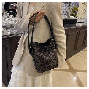 Leopard print bucket bag shown with a beige blazer and white lace skirt in a city setting