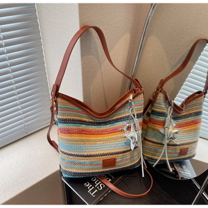 Detalle de bolsa tipo cubo tejida en colores con correa de cuero y dije de estrella