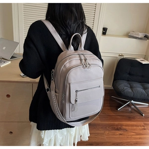 Detail of grey pebble leather backpack with ethnic woven strap and silver chain zipper accents