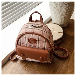 Close-up of pink checkered mini backpack with brown leather trim in soft natural light