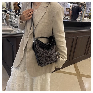 Detailed view of leopard print bucket bag with black leather trim worn over beige blazer