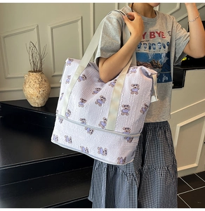 Detail of lavender travel bag with bear print and bottom zipper compartment shown on model