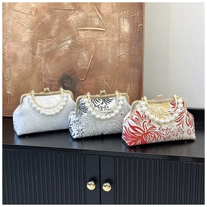 Close-up of floral jacquard embroidery on evening bags with white pearl handles