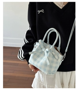 Détail d'un sac à main vichy bleu clair avec nœud et bandoulière porté par un mannequin