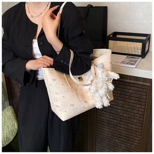 Detail of cream tote bag with bear patterns and plush rabbit pendant charm