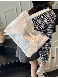 Canvas tote bag with large star-patterned bow shown in a stylish indoor shoulder carry