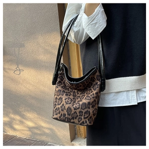 Close-up of leopard print plush bucket bag with sleek black leather handles and texture