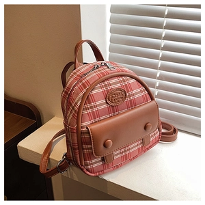 Close-up of a mini plaid backpack featuring red-white check fabric and brown leather details