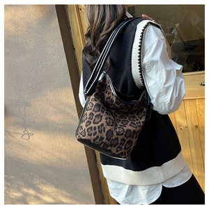 Detail of leopard print tote bag with leather straps on a warm textured background