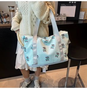 Light blue quilted travel bag featuring cartoon bear print and wide shoulder straps