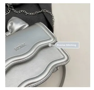 Detail of silver metallic handbag with bow design and fine stitching on the texture