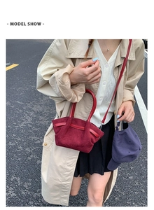 Street style shot of a burgundy suede tote bag with cylindrical handles and silver buckles
