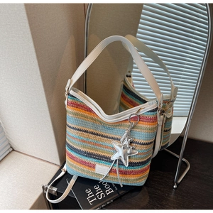 Primer plano detallado de un bolso tejido de colores con correas de cuero blanco y estrella