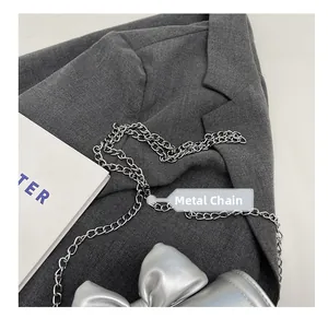 Detail of silver bow mini bag featuring polished metallic finish and delicate chain strap