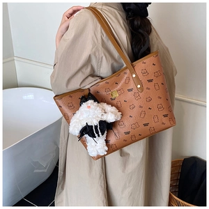 Brown tote bag with bear print and fluffy rabbit pendant shown in a minimal interior