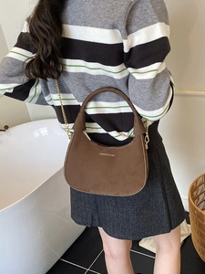 Sac à main demi-lune en daim marron avec bandoulière chaîne dorée et logo tendance