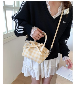 Détail du sac seau à carreaux jaune et blanc avec un grand nœud décoratif élégant