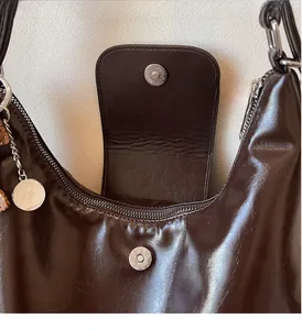 Détail du sac cabas en cuir marron brillant montrant la boucle magnétique argentée et le métal