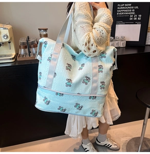 Close-up of light blue quilted travel bag with bear print and separate bottom zipper compartment