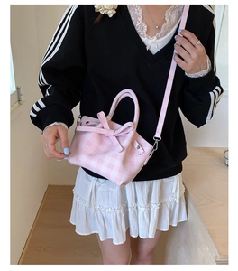 Détail du sac seau à carreaux roses avec nœud et bandoulière réglable sur le côté