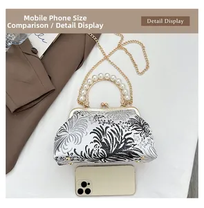 Size comparison of floral brocade shell bag with pearl handle and a smartphone