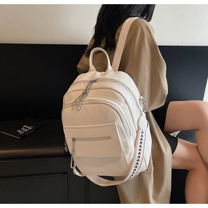 Detail of off-white pebble leather backpack featuring multi-zipper and geometric strap