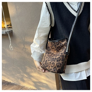Outdoor shot of a leopard print bucket bag styled with a minimalist white and black outfit