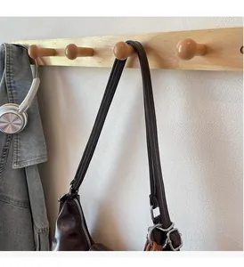 Détail des bandoulières multicouches et des boucles argentées sur un sac fourre-tout