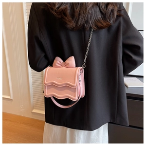 Detailed back view of a pink bow crossbody bag with a wavy flap and chain strap