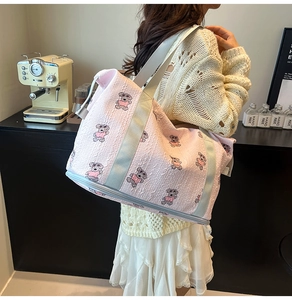 Detail view of pink quilted tote bag with bear embroidery and bottom zipper compartment