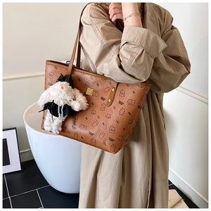 Brown leather tote bag featuring cartoon bear patterns and a white plush rabbit pendant
