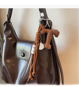 Gros plan d'un pendentif en cuir marron en forme de T avec corde sur un sac à main cabas