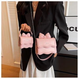 Detail of pink bow crossbody bag featuring scalloped edges and KCMK metal logo