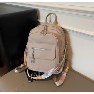 Close-up of beige lychee grain leather backpack featuring silver zippers and woven strap