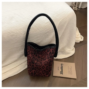 Detailed view of red and black leopard print bucket bag with faux fur texture and leather handle