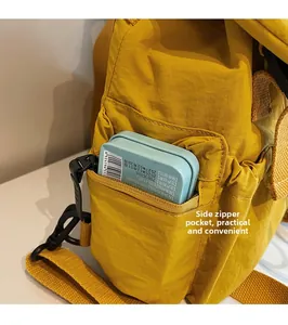 Détail de la poche latérale zippée d'un sac à dos en nylon jaune montrant le rangement