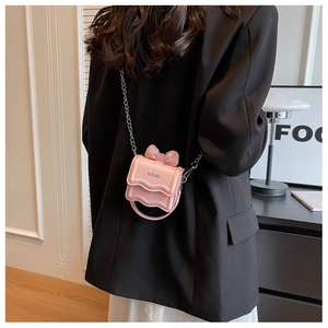 Detail of pink mini crossbody bag with bow decoration and stylish wavy flap closure