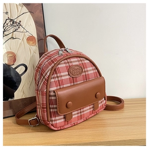 Detailansicht des rot-karierten Mini-Rucksacks mit braunen Ledertaschen und Modeschild