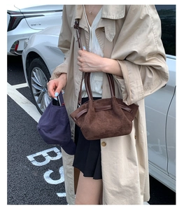 Deep brown suede tote bag with leather handles shown in a casual urban outfit context