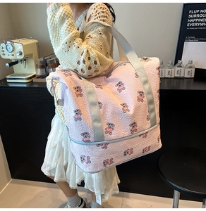 Close-up of pink foldable travel bag with cartoon bear pattern and textured fabric