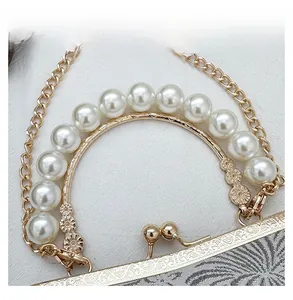 Detail view of pearl top handle and gold kiss lock on a jacquard evening shell bag