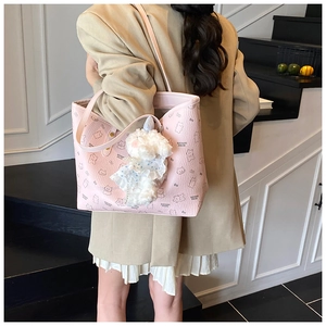 Close-up of pink tote bag featuring cartoon bear patterns and a white plush toy charm