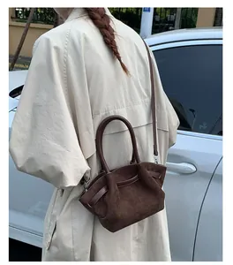 Close-up of brown suede bucket bag texture and stitching detail on a city street