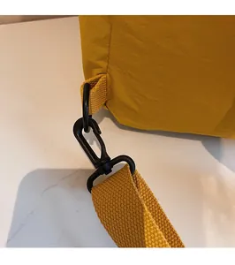Détail du crochet rotatif en plastique noir et de la sangle jaune tissée du sac à dos