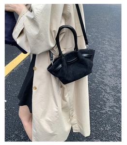 Detail view of black suede tote bag worn cross-body on a model with beige trench coat