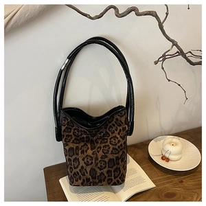 Leopard print bucket bag on a wooden table with books in a cozy lifestyle setting